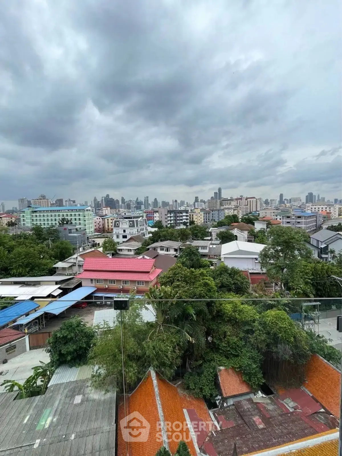 Stunning cityscape view from a high-rise balcony showcasing urban skyline and lush greenery.