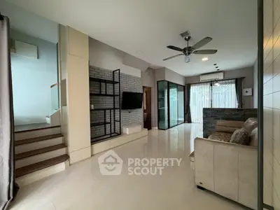 Modern living room with sleek design and open layout, featuring a staircase and large windows.