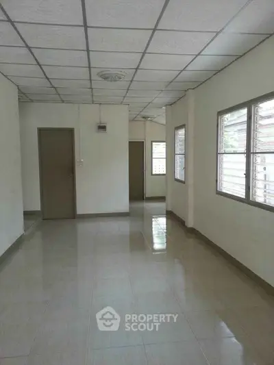Spacious empty room with tiled flooring and large windows, ideal for customization.