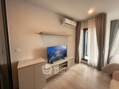 Modern living room with sleek TV setup and elegant curtains in a cozy apartment.