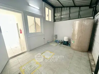 Spacious utility area with water tank and tiled flooring in modern home.