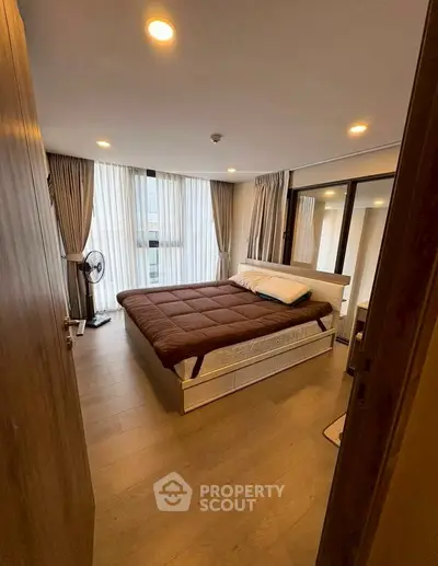 Cozy bedroom with large windows and modern furnishings, perfect for relaxation and comfort.