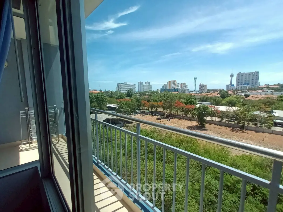 Stunning cityscape view from a modern apartment balcony with clear blue skies.