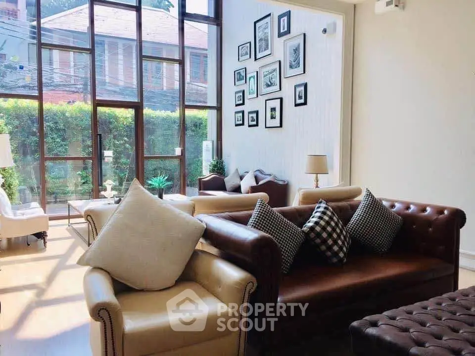 Spacious living room with high ceilings and large windows, featuring elegant sofas and stylish decor.