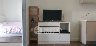 Modern studio apartment with sleek TV stand and cozy bedroom view.