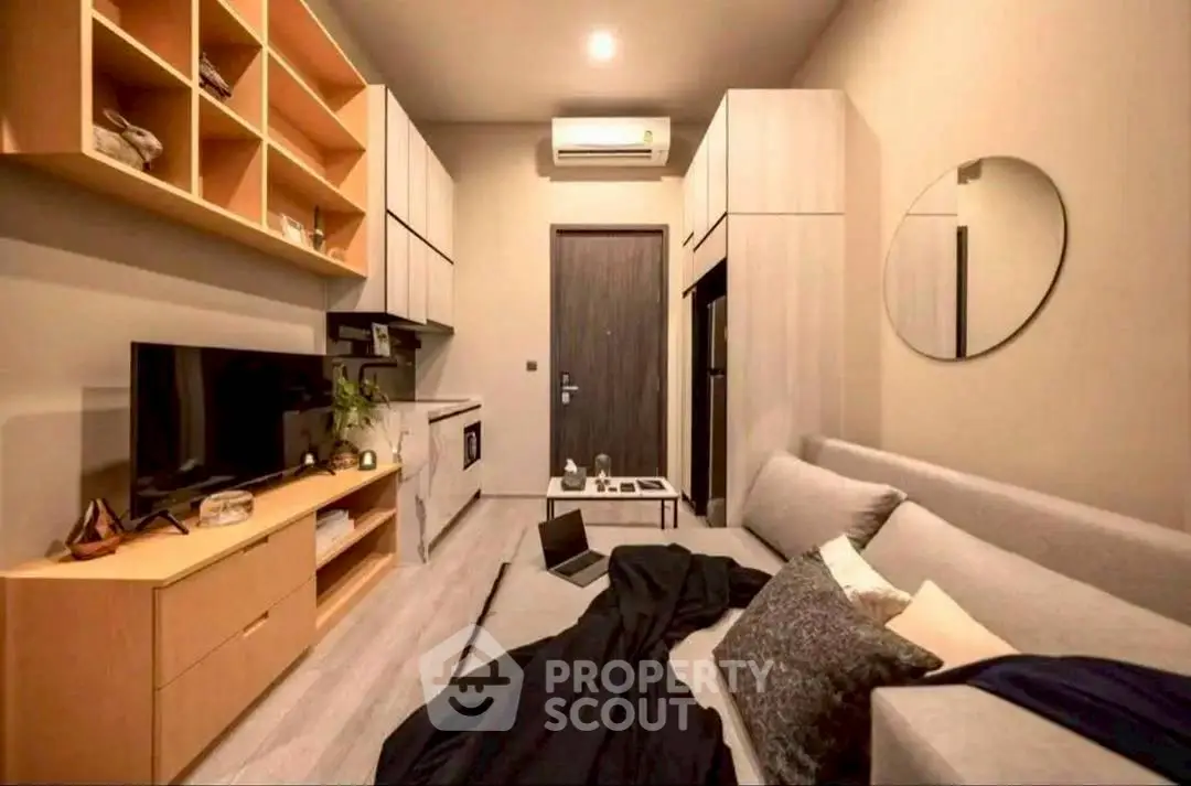 Modern living room with sleek furniture and wall-mounted TV in cozy apartment.