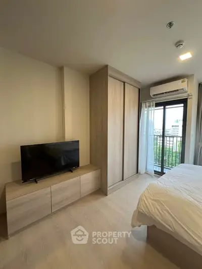 Modern bedroom with balcony view, featuring sleek wardrobe and TV unit, perfect for urban living.