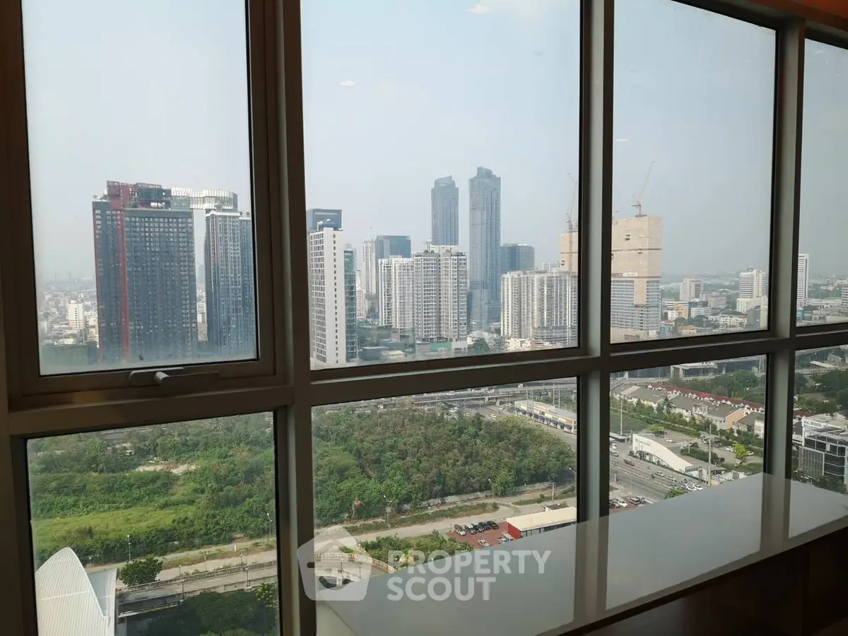 Stunning cityscape view from high-rise window showcasing urban skyline and greenery.