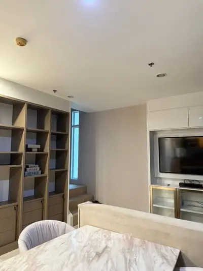 Modern living room with built-in shelves and TV unit, featuring elegant marble table.