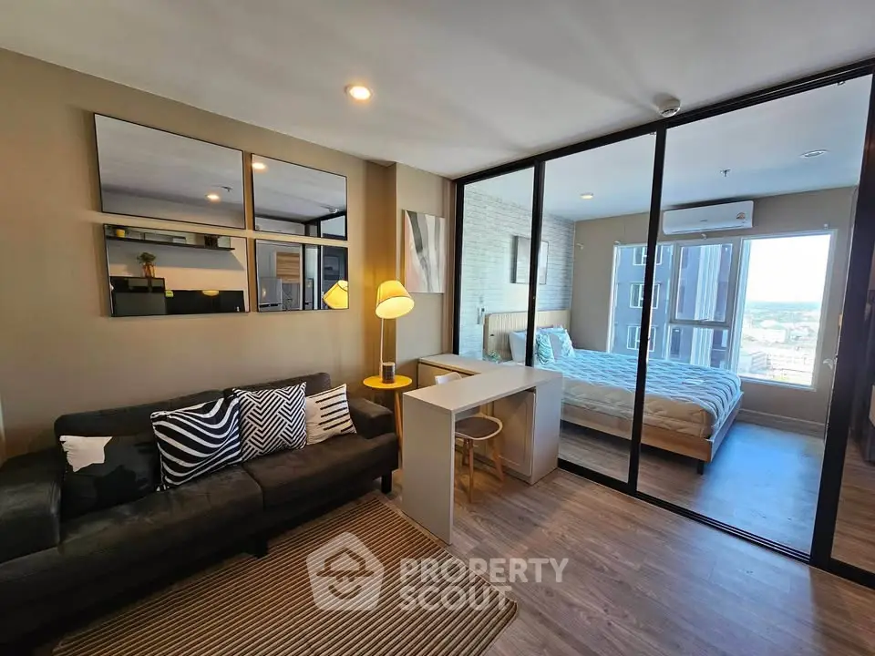 Modern studio apartment with stylish decor and city view, featuring a cozy living area and bedroom separated by glass doors.