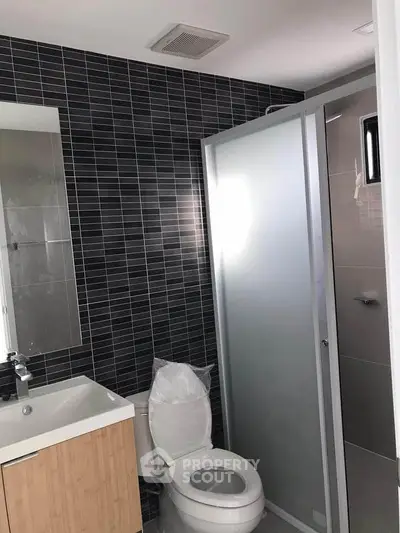 Modern bathroom with sleek black tiles and glass shower enclosure