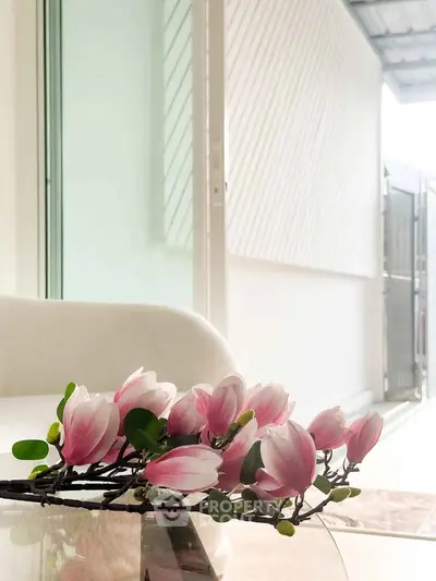 Elegant interior with modern decor and natural light, featuring a cozy seating area and stylish floral arrangement.