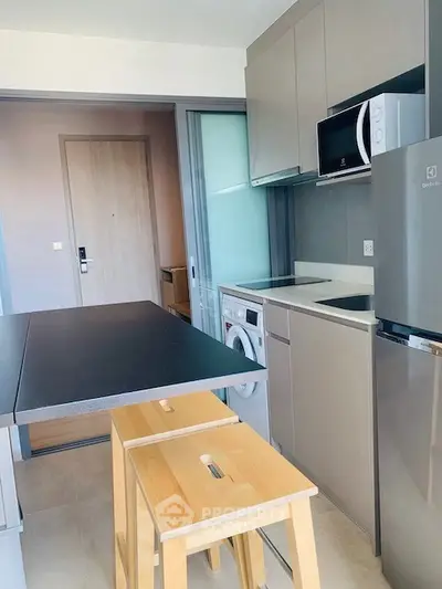 Modern compact kitchen with washing machine and microwave in sleek apartment.