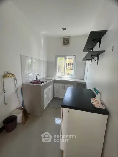 Modern kitchen with sleek countertops and open shelving, featuring a compact yet functional design.