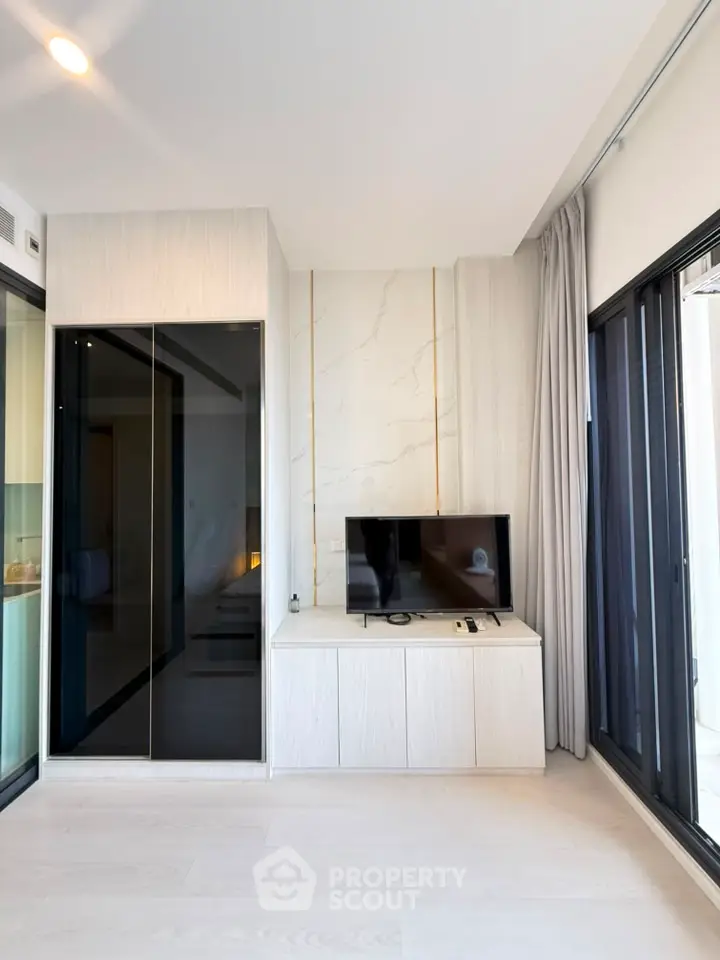 Modern living room with sleek TV unit and large windows for natural light.
