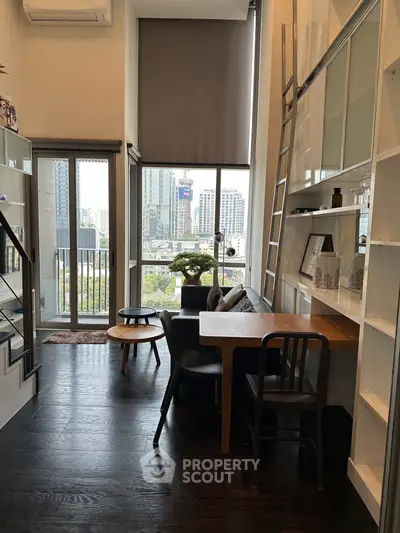 Modern loft apartment with high ceilings and city view, featuring stylish furniture and floor-to-ceiling windows.