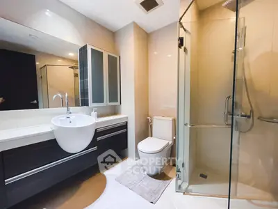 Modern bathroom with glass shower and sleek vanity in contemporary home.