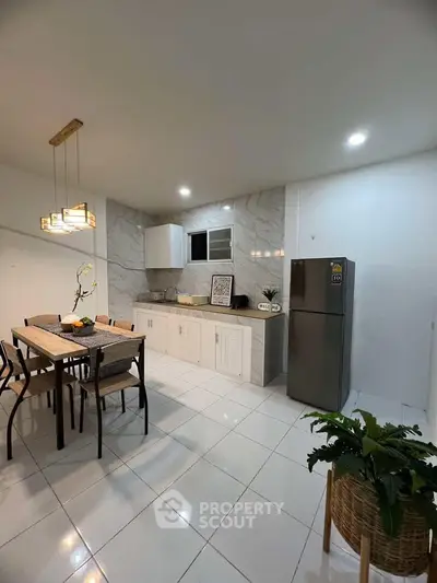 Modern kitchen with dining area, sleek cabinetry, and stainless steel fridge in a stylish apartment.
