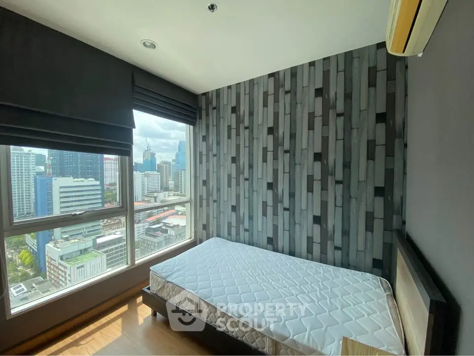 Modern bedroom with city view and stylish wallpaper in high-rise apartment.