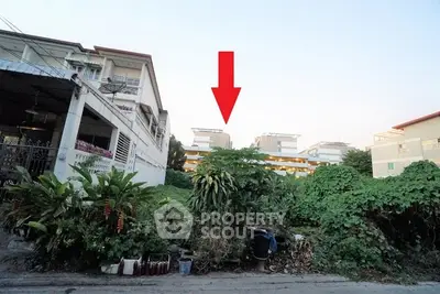 Vacant land plot with potential for development in urban area, surrounded by greenery and residential buildings.