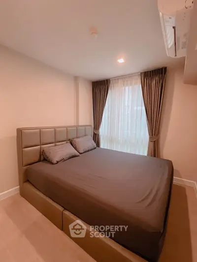Cozy bedroom with modern decor and natural light, featuring a comfortable bed and elegant curtains.