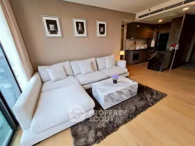 Modern living room with plush white sofa and stylish kitchen in open layout.