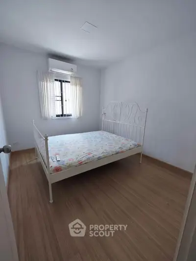 Cozy minimalist bedroom with wooden flooring and natural light