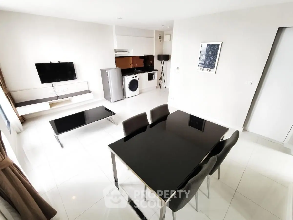 Modern open-plan living room with sleek furniture and integrated kitchen appliances.