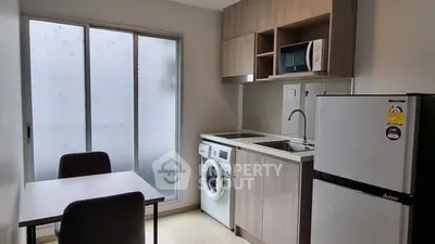 Modern kitchen with washing machine and dining area in compact apartment.