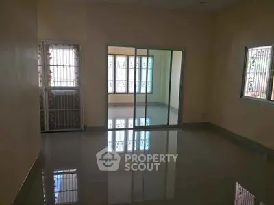 Spacious empty room with glossy tiled floors and sliding glass doors