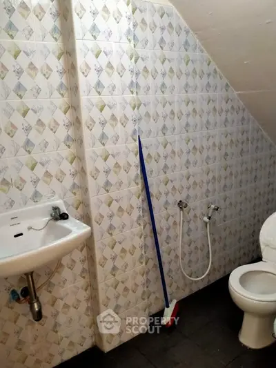 Compact bathroom with tiled walls and basic fixtures, ideal for small spaces.