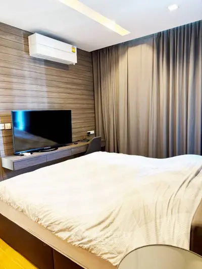 Modern bedroom with sleek design, featuring a wall-mounted TV and air conditioning unit.