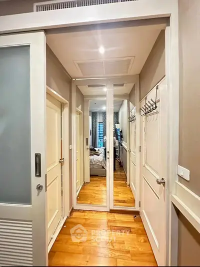 Stylish hallway with mirrored closet doors and wooden flooring in modern apartment.
