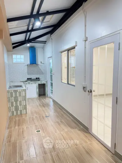 Modern kitchen with open layout and stylish wooden flooring, featuring a gas stove and ample natural light.