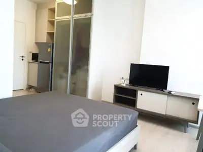 Modern studio apartment with sleek furniture and compact kitchen area.