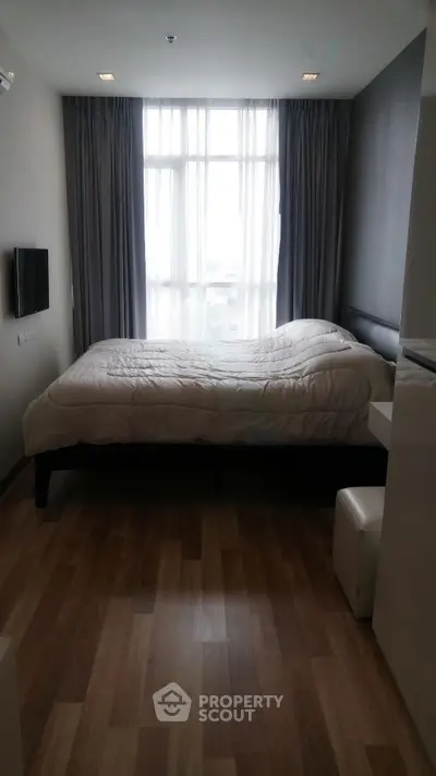 Cozy bedroom with large window and modern decor in a stylish apartment.