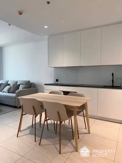 Sleek modern kitchen with integrated appliances seamlessly blending with a spacious living area, featuring minimalist decor and ample natural light.