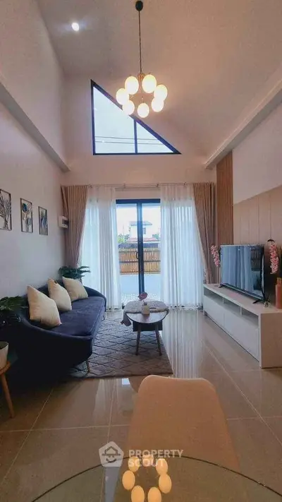 Modern living room with high ceiling and large window, stylish decor and natural light.