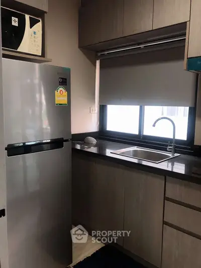 Modern kitchen with sleek cabinetry and stainless steel fridge in a compact layout.