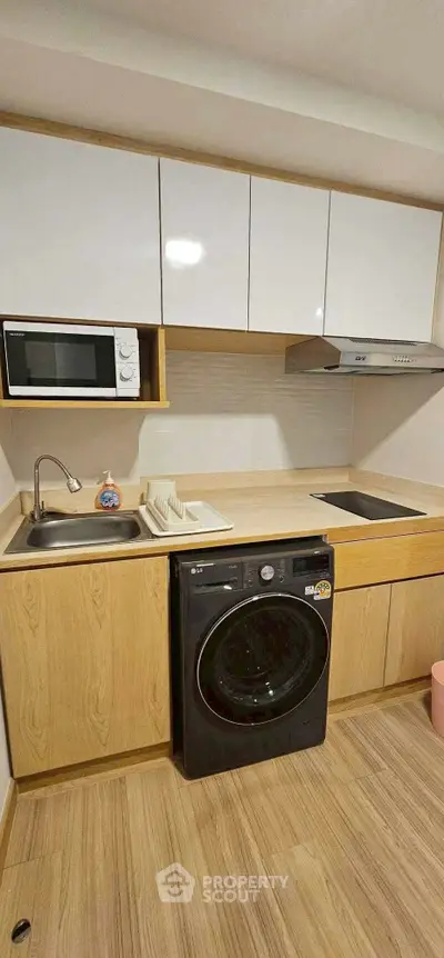 Modern kitchen with sleek cabinetry, built-in microwave, and washing machine in compact layout.