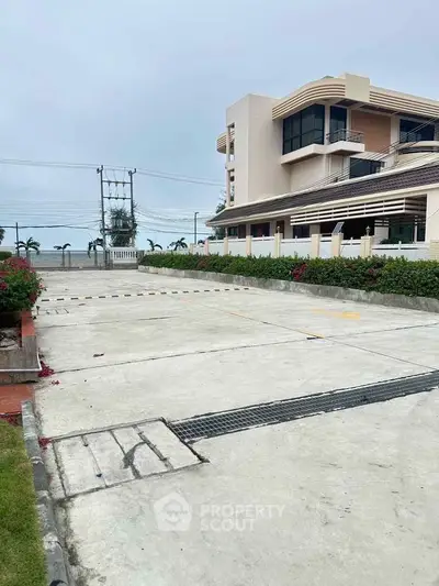 Modern building exterior with spacious parking area and landscaped greenery.