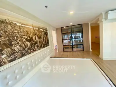 Modern living room with cityscape wall art and sleek glass partition in a stylish apartment.