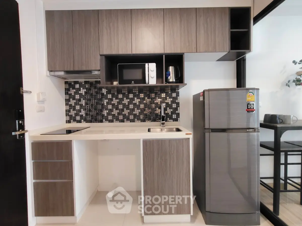 Modern kitchen with sleek cabinets, mosaic backsplash, and stainless steel appliances.
