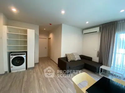 Modern living room with sleek flooring, cozy sofa, and built-in washer in open layout.