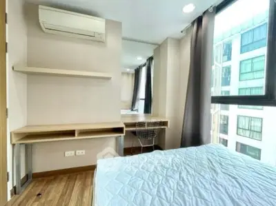 Modern bedroom with large window and built-in desk in urban apartment