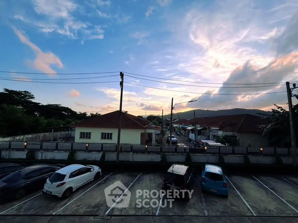 Scenic view of residential neighborhood with parked cars and sunset sky.