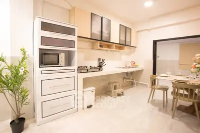 Modern kitchen with sleek cabinetry and dining area, featuring gas stove and microwave, perfect for culinary enthusiasts.