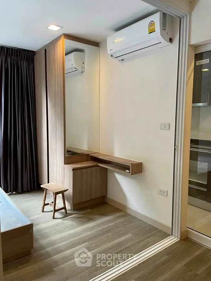 Modern bedroom with air conditioning and wooden flooring, featuring a built-in vanity and stool.