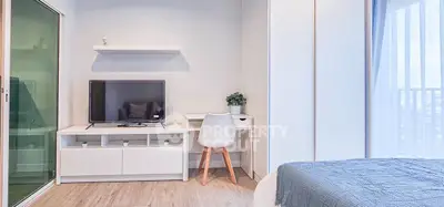 Modern bedroom with TV, desk, and balcony view in stylish apartment