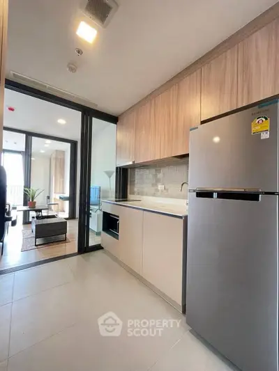Modern kitchen with sleek appliances and open layout leading to stylish living room.